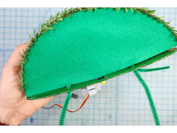 Apply hot glue to the joint at the top of the mouth only (so that the bottom is free to move up and down), and glue it to the backplate at 90 degrees.