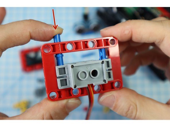 Position the servo motor inside the frame so that the holes align with the blue long pins.