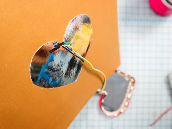 Make a hole in the cardboard to thread the wires through to the back.