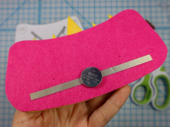 Make a loop of Maker Tape with the adhesive side out and place it on the negative side of the battery.