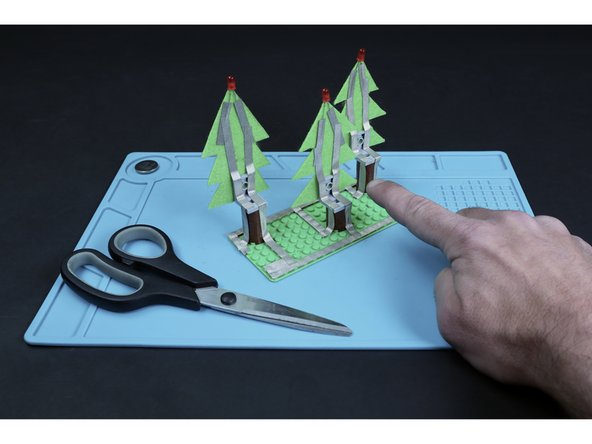 Measure, cut, peel and stick tape paths that lead from the ends of the existing left LED leg paths, down their respective trunks and to their corresponding short segments from the previous step.