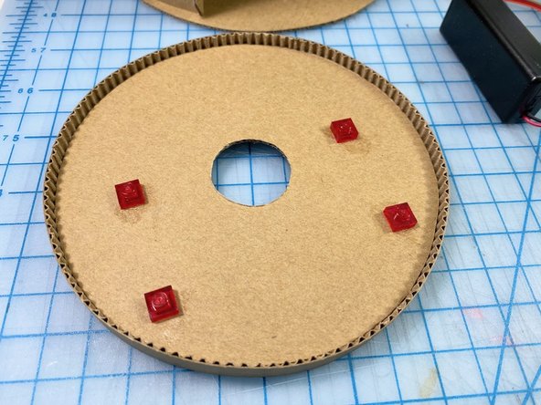 We made a top with another circle of cardboard and cut a circle out of the center large enough to put the battery pack through.