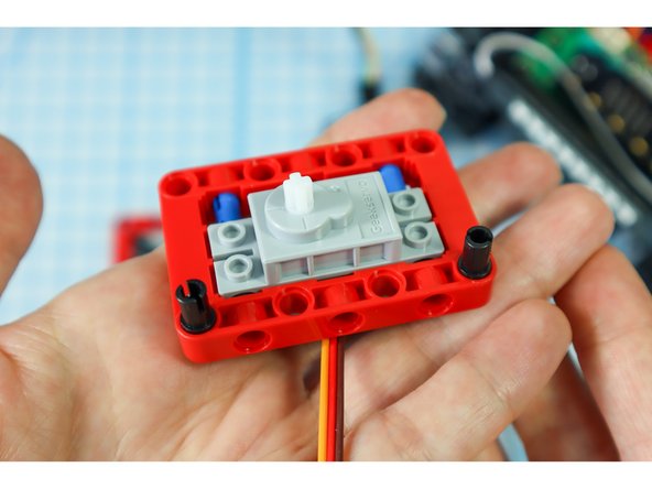 Add two black pins to the bottom of the frame, on the same side as the motor as shown.