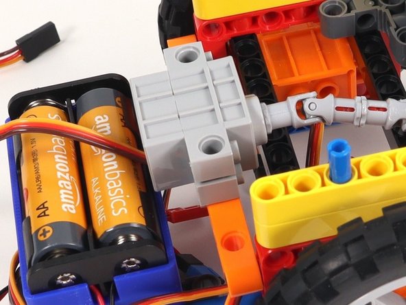 Connect the two black pins on the servo to the orange beam with side holes on the back of the Rover. The wires should be facing the bottom of the Rover.