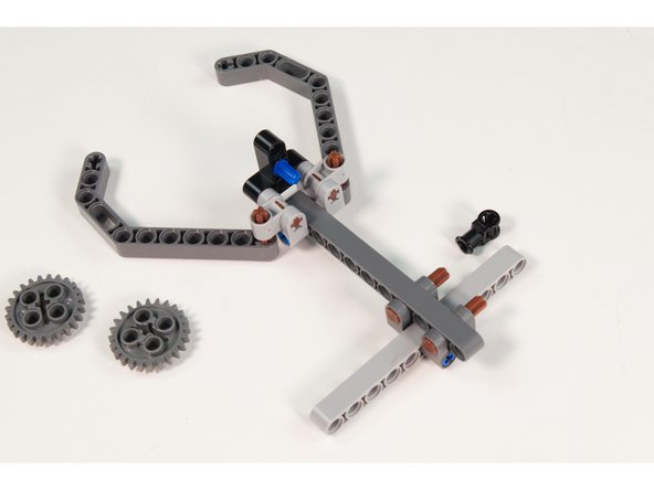 Press the LEGO Technic Through Axle Connector with Bushing onto the frontmost LEGO Axle 4 with End Stop  on the back of the main assembly with the axle hole oriented upwards.