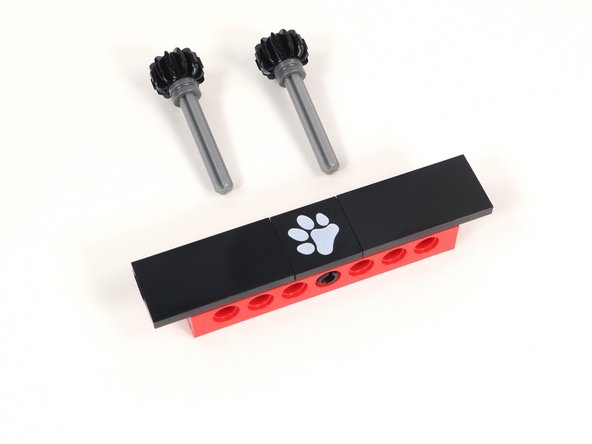 Insert the axles through the holes to the left and right of the center hole (that has a black pin in it) from the back so the open end of the axle is facing the front.