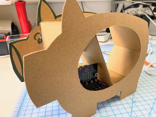 We stood the pig up and used hot glue to attach the box to the two pig sides. We made sure that all four feet were flat before gluing so that the pig would be sturdy when standing.