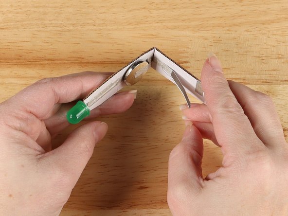 With the battery facing you, gently bend the cardboard somewhere between the battery and the switch.