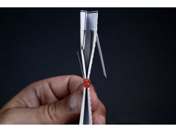 Seat the LED as shown with each leg on opposite sides of the shape.  These legs should be right over the area where the Maker Tape is located on the outside of the shape.