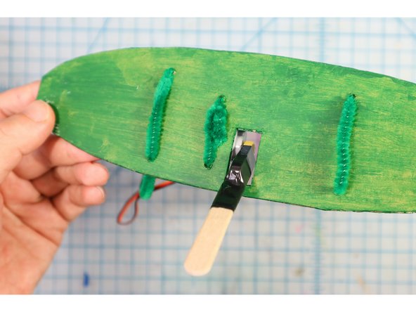 Add pipe cleaners through the remaining holes as shown. These will be used like giant &quot;twist ties&quot; to tie the backplate to the trunk of the tree.