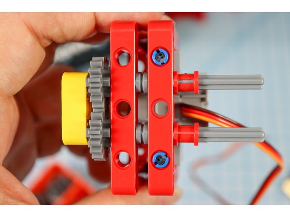 Insert two red full bushings, another yellow beam, two half beams (one on each axle), and two more red full bushings as shown.