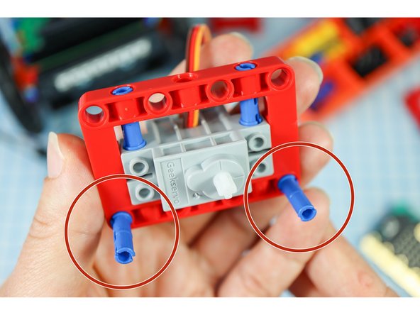 Add two blue pins to the front of the red frame as shown.