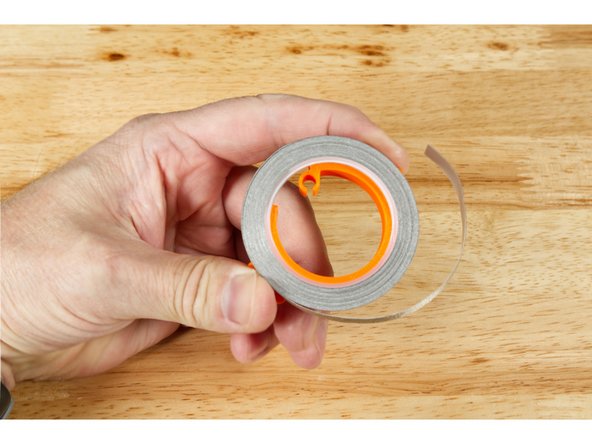 Hold the tape roll holder in your hand so you can gently squeeze it using the two tabs on the side. You should be able to slide the tape roll onto the holder.