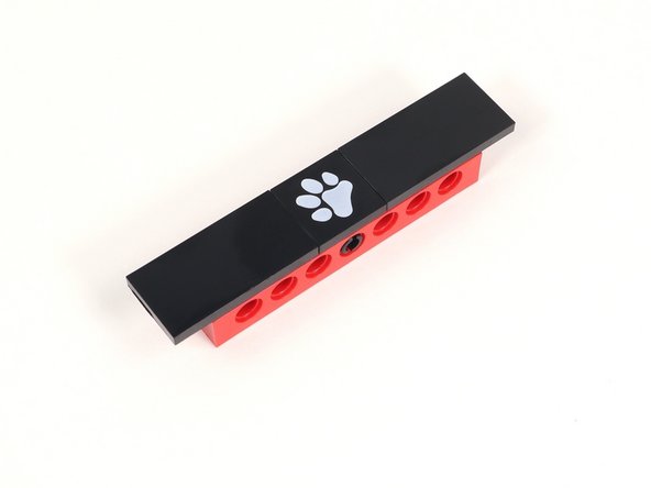 Add a 2x4 tile on either side of the paw print tile. Each of those tiles should hang off the build by one column of studs.