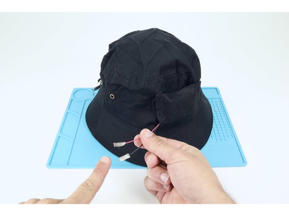 Cut two small pieces of Maker Tape and sandwich the metal ends of each of the two wires leading from the battery pack just as you had each of the individual LED legs earlier. The black wire is negative and the red wire is positive.