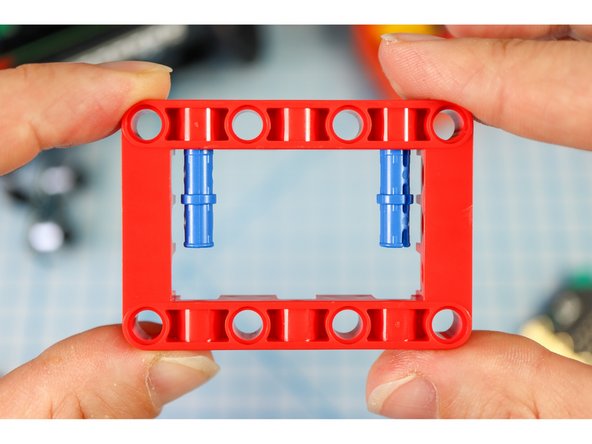 Get a red frame piece, two long pins, and the gray servo motor.