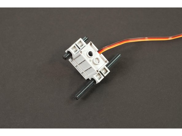 The LEGO Compatible servo has two holes for side mounting. We're going to slide the LEGO Axle 8 (3707) and the LEGO Axle 4 (3705) through the holes, making sure we've got the shorter one on the end closest to the servo shaft.