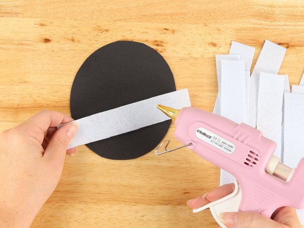 Use glue to assemble the Mummy with the strips in any arrangement you prefer, leaving a small area for the eyes. The strips should go passed the edge of the oval. We will trim and glue the edges in the next step.