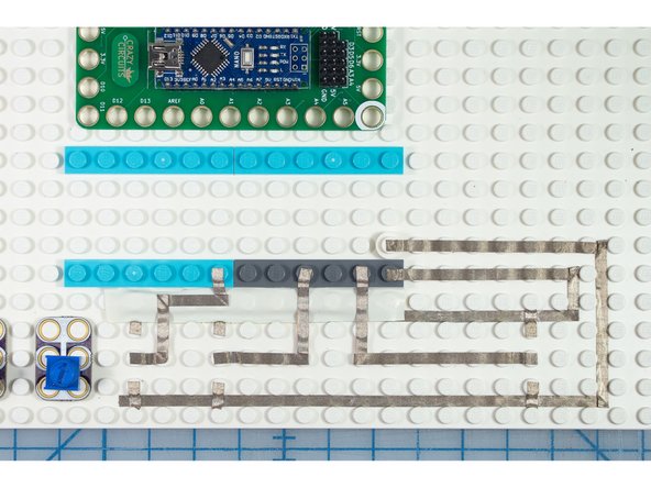 Tip: Use the space between the LEGO pegs to run the Maker Tape - a small stick is helpful to guide the tape in place - Where the maker tape needs to cross, use the top of the LEGO pegs to hold it over the other piece, or use electrical tape between them
