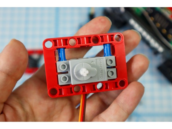 Add two black pins to the bottom of the frame, on the same side as the motor as shown.