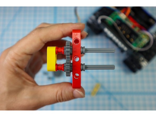 Push the axles through a red frame, then add half bushings to the gray axles to secure it.