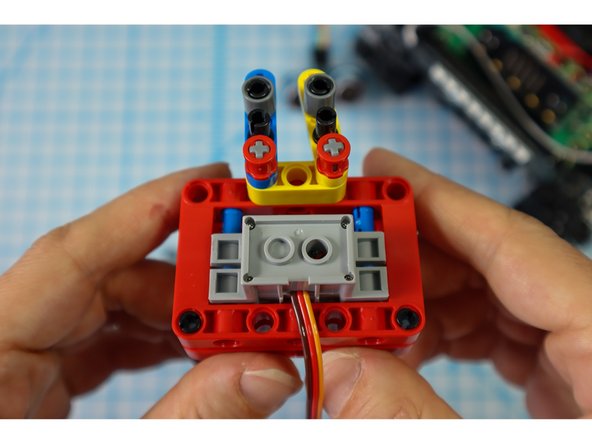 Add a single beam to the top pins as shown. These will connect to the paper arms in a later step.