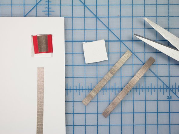 Cut two pieces of Maker Tape. Adhere them to the square piece as shown, with a gap between them.