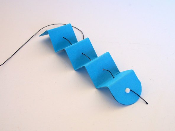 Add a drop of glue (or tape) on the knot to make sure it doesn't pull through the paper