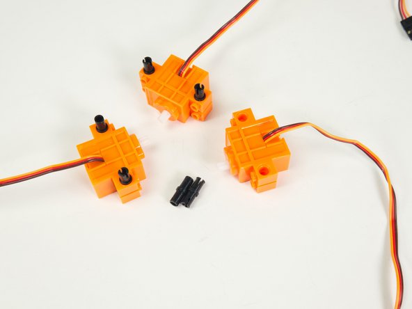 With the wires of the servos facing up, add the black pins as shown.