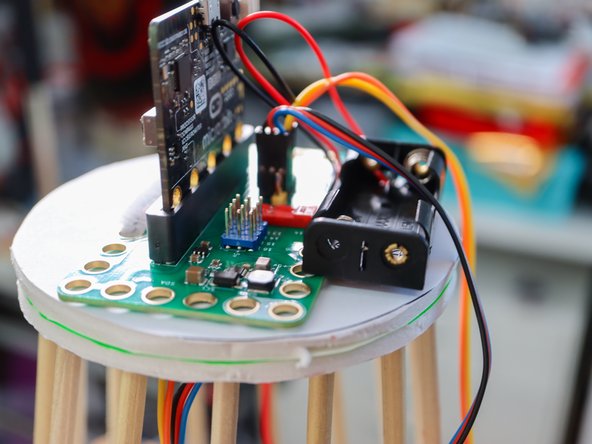 Add a glue dot or a dab of hot glue to the top of each dowel and place each dowel inside the holes on the circle piece as shown.
