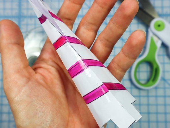 Starting at the bottom, roll the horn piece into a cone and align the edge, taping it together.