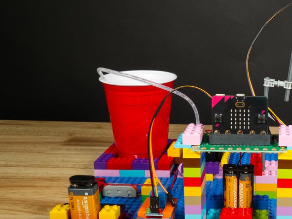 We used a red plastic cup for our demo, and we built up a little wall of LEGO bricks around it to help hold it in place.