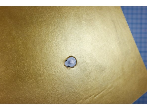 Put a 1/2 inch hole in the cardboard where the center of the gauge will go. Then, add a notch so that the motor sits flush with the top of the cardboard as shown.