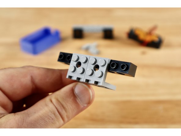 Connect 2 of your (2x2) 90 degree brackets to the outside edges of one of your 2 remaining 1x8 bricks with holes to create the build shown in slide 1.