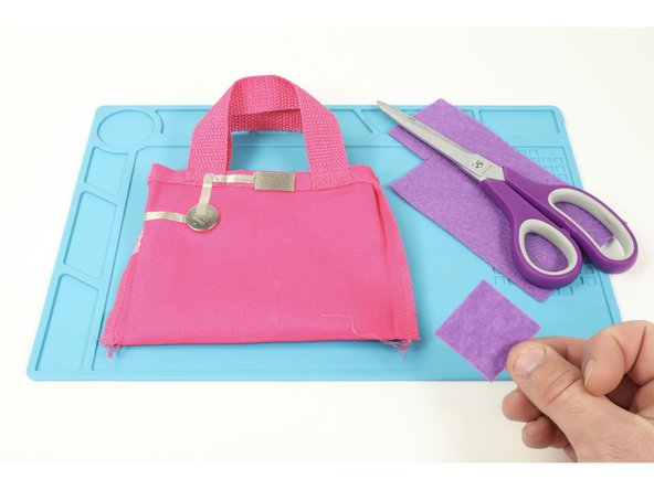 So that your battery doesn’t get knocked loose when putting things in your bag, cut and hot glue a small square of felt just a little bit bigger than your battery where shown.