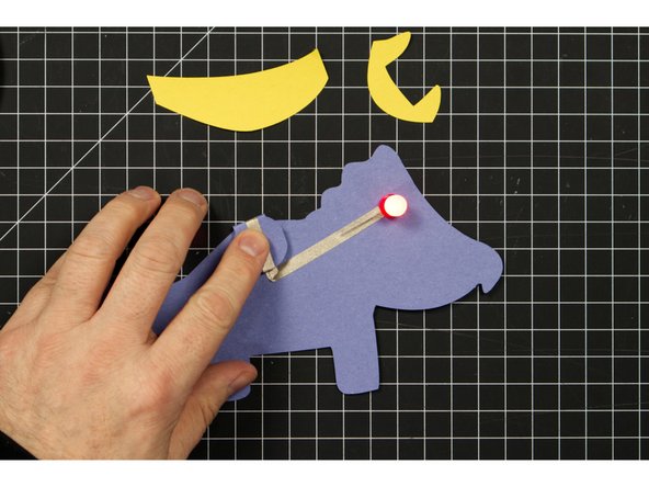 Fold down the round battery holder section on the back so that the positive line of tape make contact with the top of the battery.