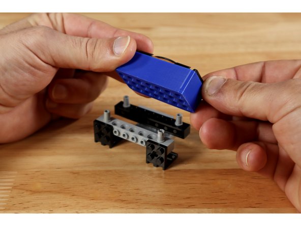 Connect 2 more of your (2x2) 90 degree brackets to your last 1x8 brick with holes to create the build shown in slide 2. These brackets should occupy the 4 middle studs of the 1x8 brick with holes.