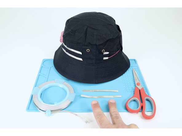 As shown in photos 2 and 3 measure/cut/ peel/stick a Maker Tape path that connects the upper negative path of the LED portion of your circuit to the black negative pad of the battery pack. Then connect the remaining lower path from the LEDs to the red positive pad of the battery pack.