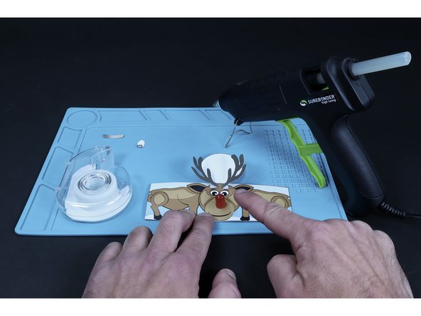 Glue the two antlers in place as pictured by applying a dot of hot glue to the striped areas on the tube body and pressing the folded, striped parts of the antlers to those areas.