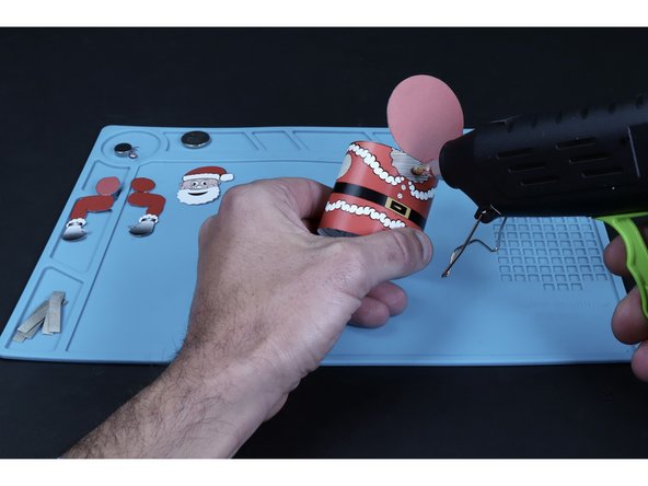 Apply hot glue to the striped area shaped liked Santa's beard. Press the matching portion of Santa's head into place.