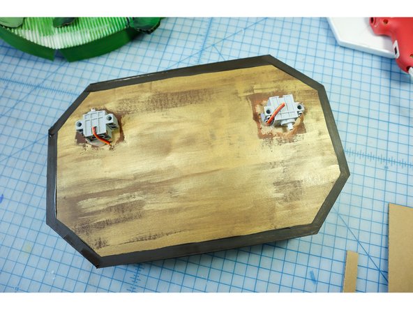 Paint the plaque medium brown, then use gold paint to dry brush over it. Finally, create a border with dark brown.