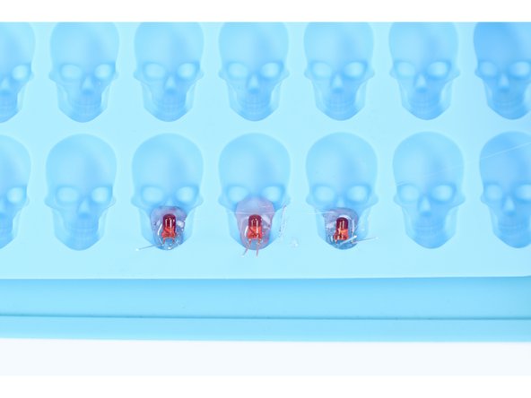 Now take an LED with legs bent and place it atop that glue as shown, holding it in place for 30 seconds. This allows this small amount of glue to harden BELOW the bulb (actually the front of the FINISHED object) and holds the LED in place before final filling. Repeat this process one-by-one for each remaining LED in your project.
