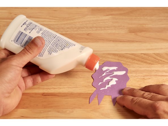 Add some glue or tape to the middle of the remaining shape taking care to keep the arms and the ruffled outer edges free of stickiness.