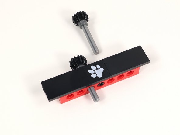 Insert the axles through the holes to the left and right of the center hole (that has a black pin in it) from the back so the open end of the axle is facing the front.