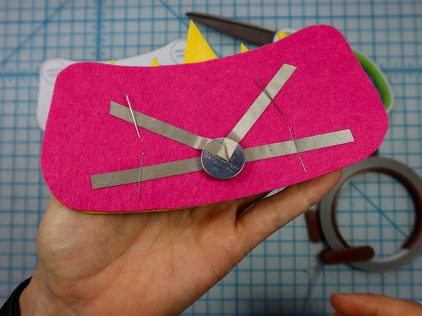 Fold each LED leg down flat against the felt, making sure the longer, positive legs touch the &quot;V&quot; and the shorter, negative legs touch the horizontal piece.