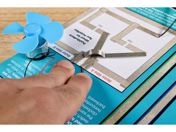 Connect the black motor wire to the end of the upper part of the criss-cross nearest to the &quot;Motor Wire B&quot; label. Use a small piece of Maker Tape that you measure, cut, peel, and stick as shown.