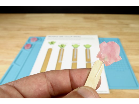 Place the LED over the end of your popsicle stick so that the short positive leg is in front  (photo 2) and the long positive leg is on the opposite side of the stick (photo 3).