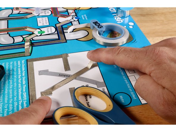 Measure, cut, peel, and stick the three Maker Tape segments that make up the lower part of the criss-cross.