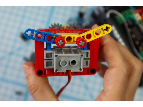 Continue adding components to the axles as shown: the yellow beam, a half beam on each axle, and full red bushings on each axle.