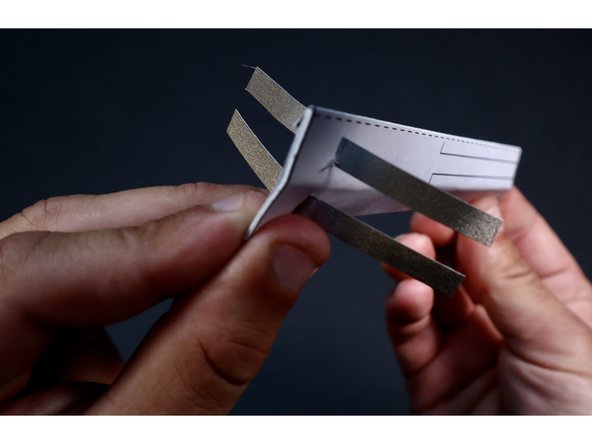 Thread each of the two 3.5&quot; sections of Maker Tape  through those slits with the sticky side facing down toward the paper. Feed them through to their approximate halfway point.